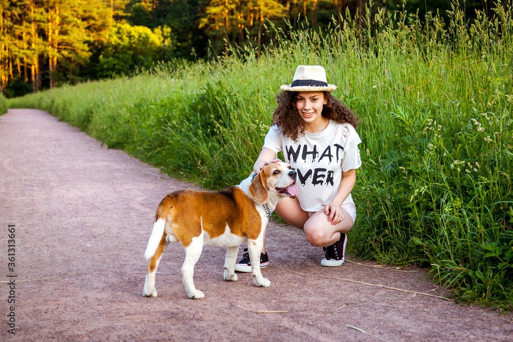 A girl with a Beagle on a path in the grass.