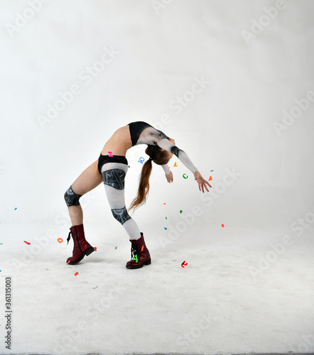 beautiful girl in a robot suit throws up multi-colored letters and does gymnastic exercises on a white background