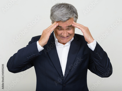 Portrait of stressed senior businessman in suit having headache