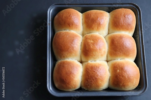 Freshly baked homemade Mumbai style golden Ladi pav or soft dinner bread roll in a baking tray. made out of all-purpose flour, yeast, milk and salt. Ideal for pav bhaji or missal pav. Copy space.