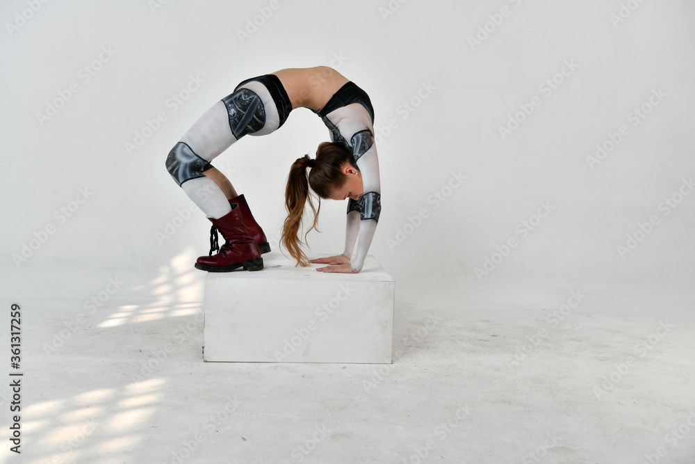 beautiful girl in a robot suit makes acrobatic movements on a white background