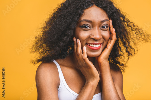 Portrait of beautiful positive african american black woman standing isolated over yellow background.