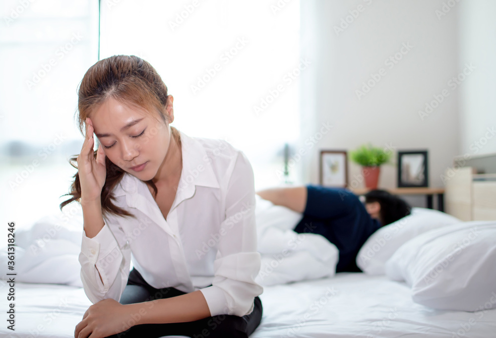 Young lovers, they are having problems with quarrel. Woman is sitting on the bed and she is having a headache with a problem. Young lovers, they are having problems with quarrel. Woman is sitting on the bed and she is having a headache with a problem.