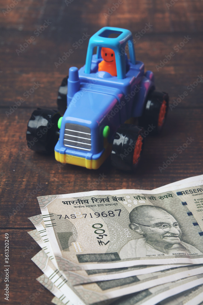 Plastic toy tractor with Indian currency on wooden table - Vehicle loan concept
Plastic toy tractor with Indian currency on wooden table - Vehicle loan concept