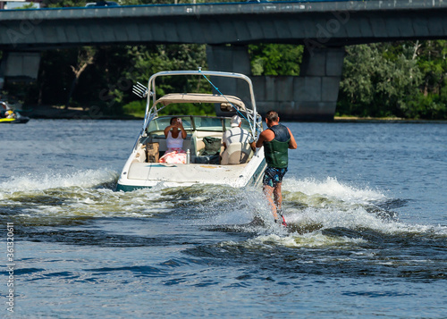 A man on a wakeboard surfing on the river for a jet ski