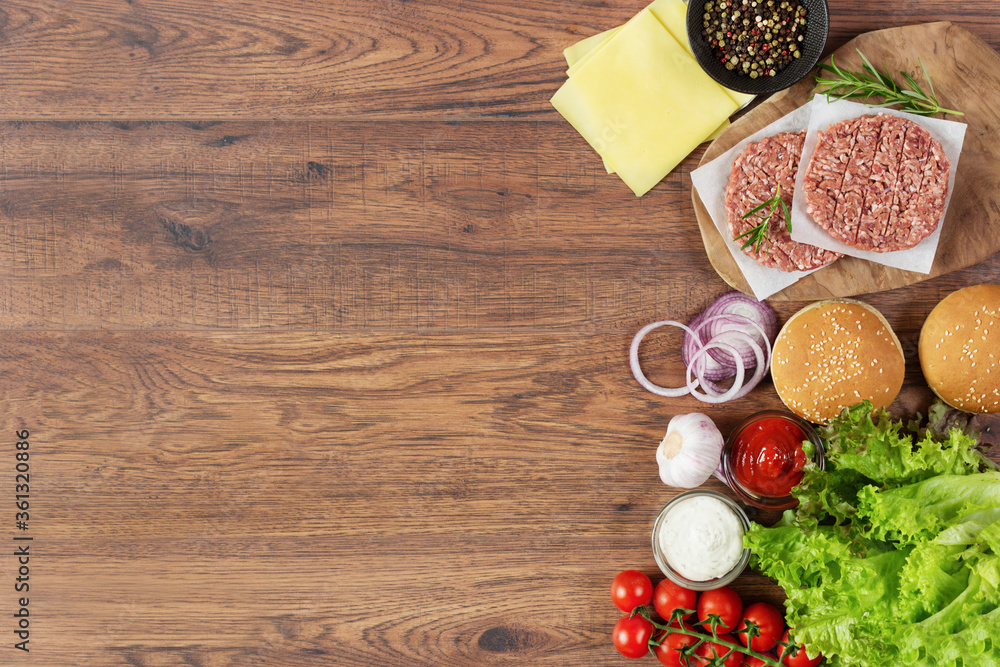 Fresh raw ingredients for homemade burger on wooden background.