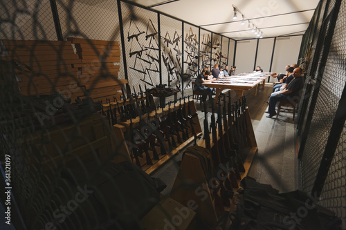 Automatic rifles lie foreground on the shelf in the armory