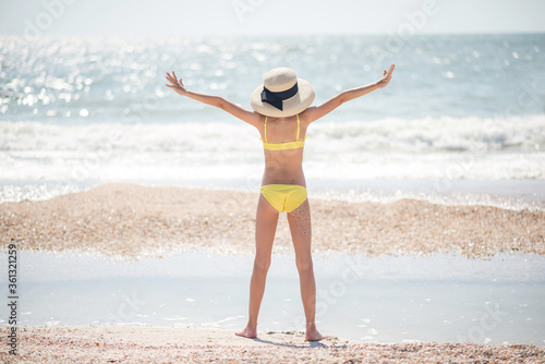 young woman in bikini. girl in hat. Beautiful girl with long hair in a yellow swimsuit by the ocean. Travel and relaxation. Family Contact. sports and recreation