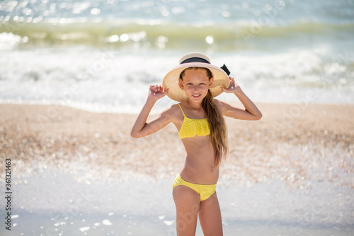 young woman in bikini. girl in hat. Beautiful girl with long hair in a yellow swimsuit by the ocean. Travel and relaxation. Family Contact. sports and recreation