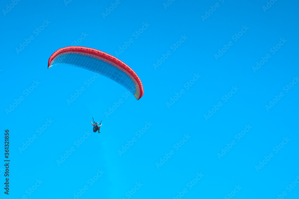 Doubles paragliding against a clear blue sky. A multi-colored papaplan flies in the clear sky closeup. Doubles paragliding against a clear blue sky. A multi-colored papaplan flies in the clear sky closeup.