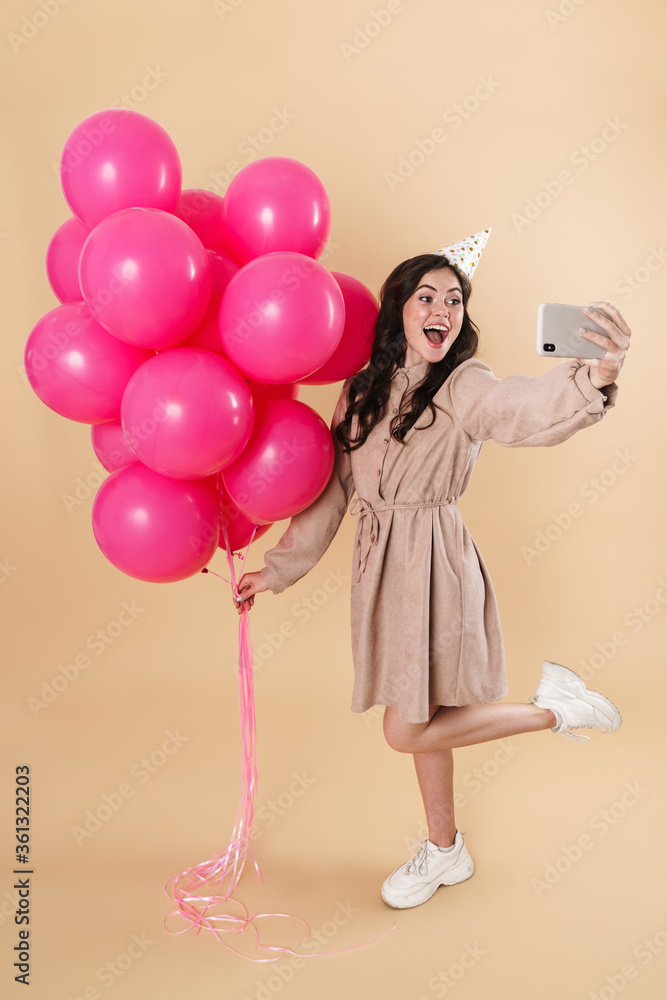 Image of excited woman taking selfie with pink balloons on cellphone Image of excited woman taking selfie with pink balloons on cellphone