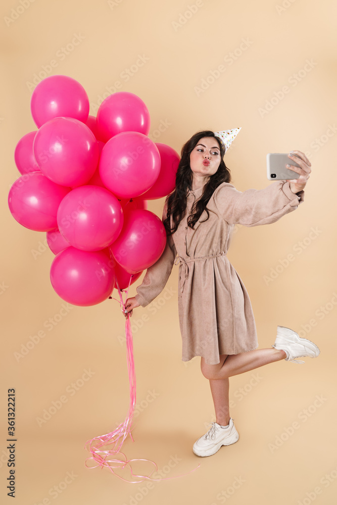 Image of happy cute woman taking selfie with pink balloons on cellphone Image of happy cute woman taking selfie with pink balloons on cellphone