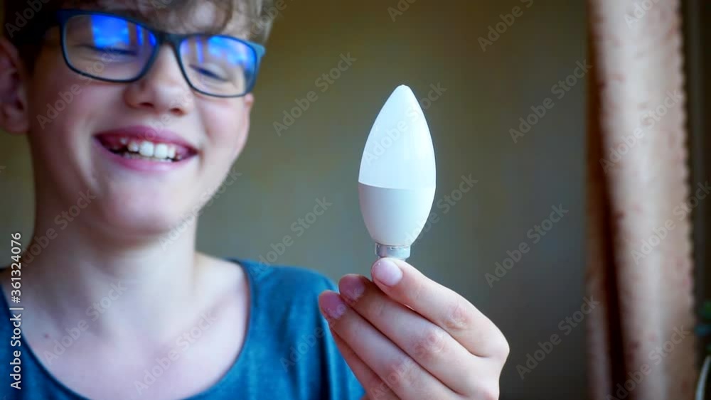 school age boy with glasses holds a light bulb. school age boy with glasses holds a light bulb.