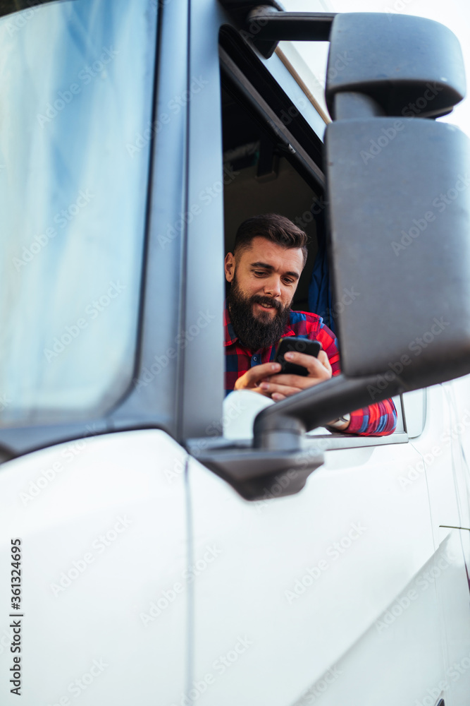 Young handsome bearded man driving his truck and using smart phone. Young handsome bearded man driving his truck and using smart phone.