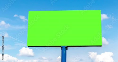 advertising billboard outdoor with green blank screen against beautiful blue sky time lapse with cumulus clouds at summer. empty display with copy space and chroma key. natural landscape background