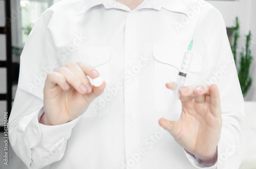  girl in a white coat holds a tablet and syringe on a white background