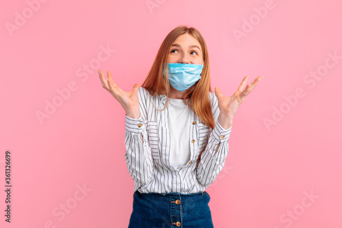 excited, shocked, happy girl in a medical protective mask on her face, looking away, on an isolated pink background
