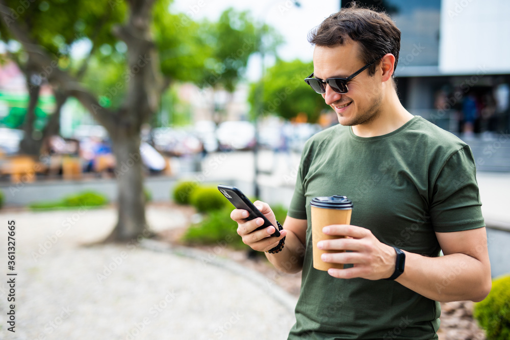 Handsome young man write sms and drink coffee on the street Handsome young man write sms and drink coffee on the street