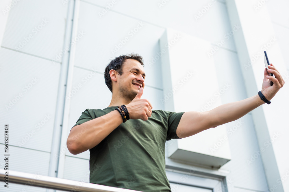 Cheerful happy man making with thumbs up on selfie on the street Cheerful happy man making with thumbs up on selfie on the street