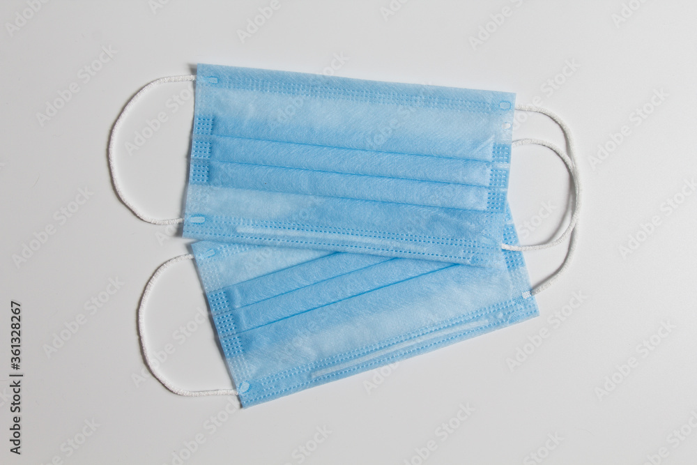 disposable medical masks in blue with elastic bands with a nose clip on a white background disposable medical masks in blue with elastic bands with a nose clip on a white background