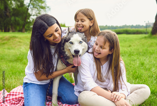 Happy family with husky dog lying on grass in summer park.