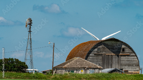 Electric generating windmills on the prairie vintage and new technologies at a prairie farm next to an old weathered barn. Yesterday and today's energy solutions. Various crops, color and B&W full sky © Impassioned Images
