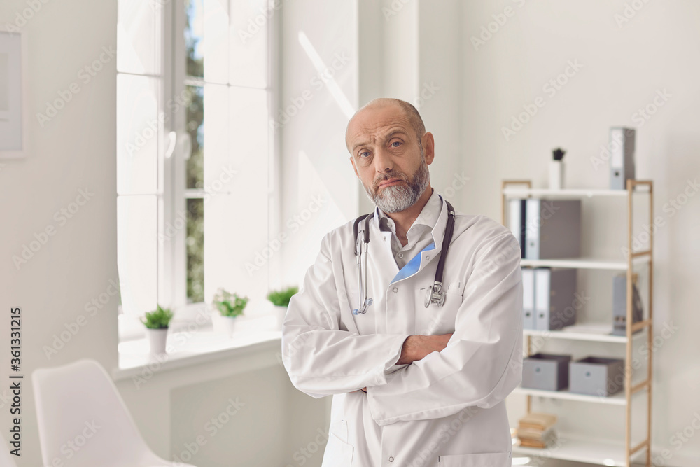 Portrait of senior age gray bearded family doctor looking at camera in private practice office. Portrait of senior age gray bearded family doctor looking at camera in private practice office.