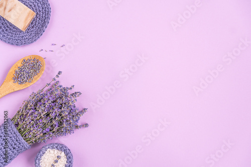Lavender flowers are arranged on a purple background. cosmetic set with lavender herbs, handmade soap bars and sea salt. Flat lay, copy space