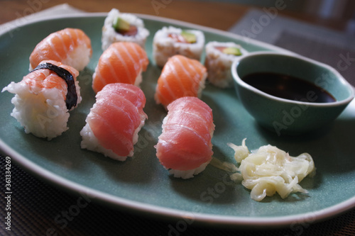 Japanese sushi food. Sushi set on green plate served with ginger and soy sauce. Sushi rolls, salmon nigiri, shrimp nigiri, tuna nigiri