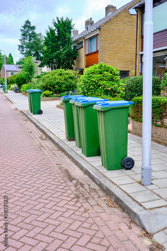 A group of Garbage cans on the side of the road waiting to be emptied. GReen blue waste bin in street, the Netherlands