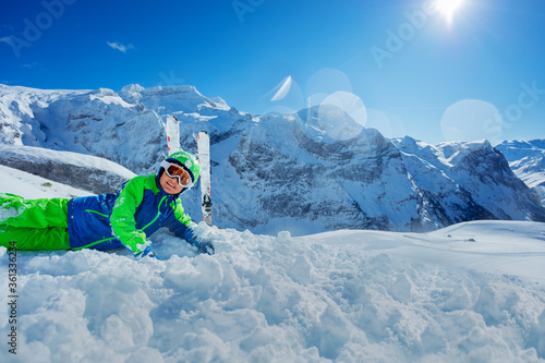 Cute boy having fun resting in snow over sunny mountain panorama copy space