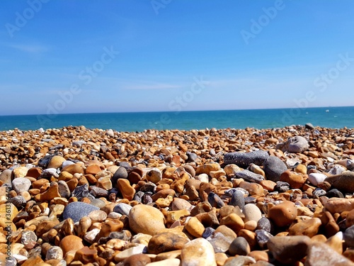Beautiful beach landscape with colorful stones and blue sky. Sea peblles beach. Beautiful nature.