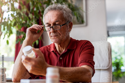 Senior man taking prescription medicine at home
