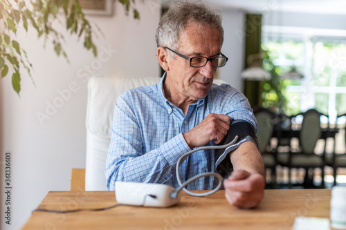 Senior man using medical device to measure blood pressure
 photo