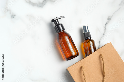 Cosmetic sale concept. Flat lay amber glass bottles and shopping bag on marble background. Top view.