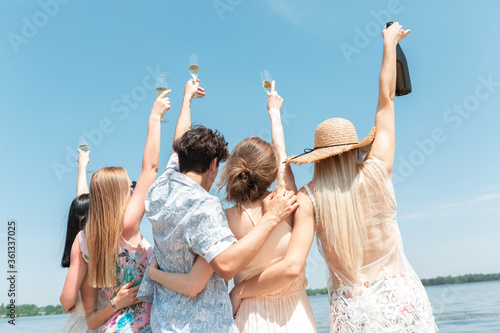 Drinking, clinking, cheers. Seasonal feast at beach resort. Group of friends celebrating, resting, having fun in sunny summer day. Look happy and cheerful. Festive time, wellness, holiday, party.