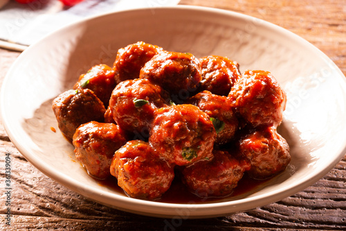 Traditional spicy meatballs in tomato sauce on wooden background. Selective focus.