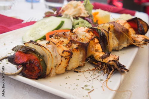 Delicious seafood dish from traditional Madeira island cuisine - mixed fish skewer with cod fish, tuna, prawns, scallops and vegetables prepared on bbq