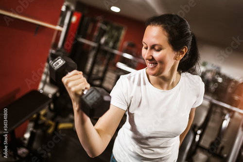 Woman working out in gym uses weights