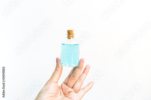 Alcohol gel in glass bottle in girl hand on white background, hand sanitizer, covid 19 cleaning gel