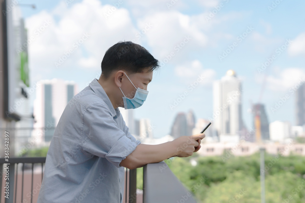 Businessman mask using mobile phone app texting outside of office in urban city with skyscrapers buildings in the background. Businessman mask using mobile phone app texting outside of office in urban city with skyscrapers buildings in the background.