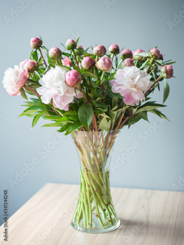 A bouquet of peonies in a transparent glass vase. Pink and white peonies. Selective focus. Artistic style.