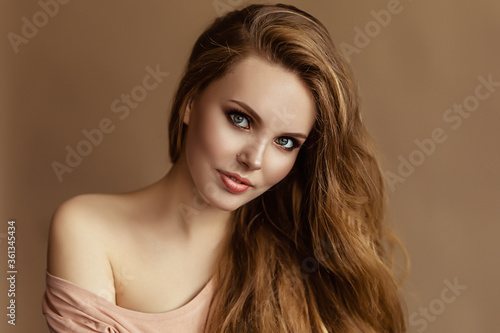 Portrait of young european woman, caucasian beautiful lady with light thick long hair, nice model wtih green eyes and nude makeup, dame on beige backgound