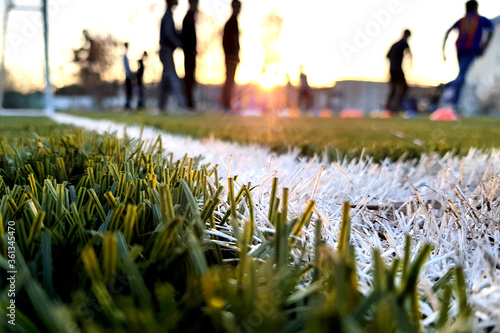 Close the artificial lawn with a white stripe and blurred football against the background photo