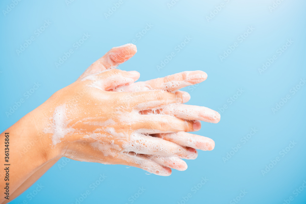 Closeup body care Asian young woman washing hands with soap have foam, hygiene prevention COVID-19 or coronavirus protection concept, isolated on blue background Closeup body care Asian young woman washing hands with soap have foam, hygiene prevention COVID-19 or coronavirus protection concept, isolated on blue background