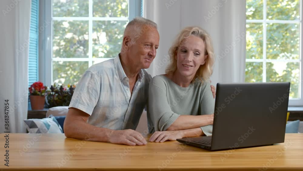 Mature couple browsing internet on laptop relaxing at home Mature couple browsing internet on laptop relaxing at home