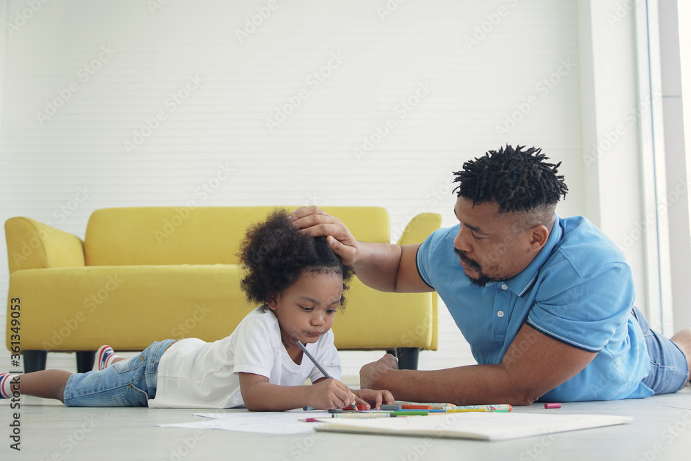 Black African American family dad son drawing together at home. Young father lying on the floor and take care his kid child boy while drawing coloring pictures Black African American family dad son drawing together at home. Young father lying on the floor and take care his kid child boy while drawing coloring pictures