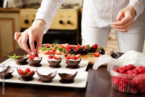 the process of preparing and decorating dessert handmade chocolate cups with whipped cream and berries. the concept of a delicious summer holiday. selective focus.