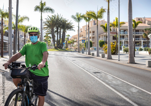 Alone man with yellow helmet and tshirt cycling in Tenerife in the deserted city street due to coronavirus, crisis of tourism