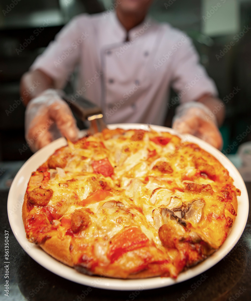Food concept Prepare a traditional Italian pizza. White chef uniform In the modern restaurant kitchen ready to eat